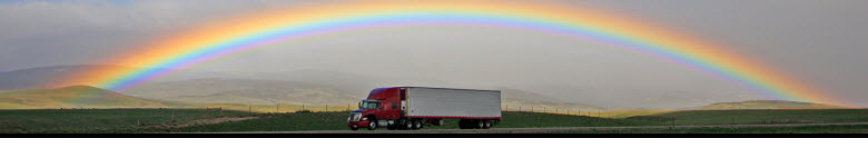 semi truck with rainbow showing in sky