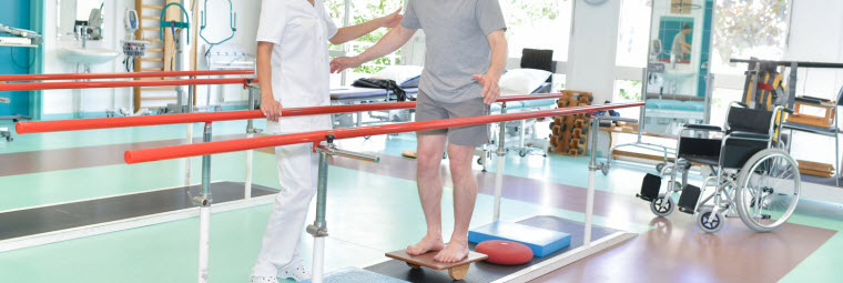 man balancing with physiotherapist