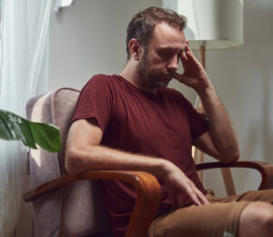 Man with headache sitting in chair at home